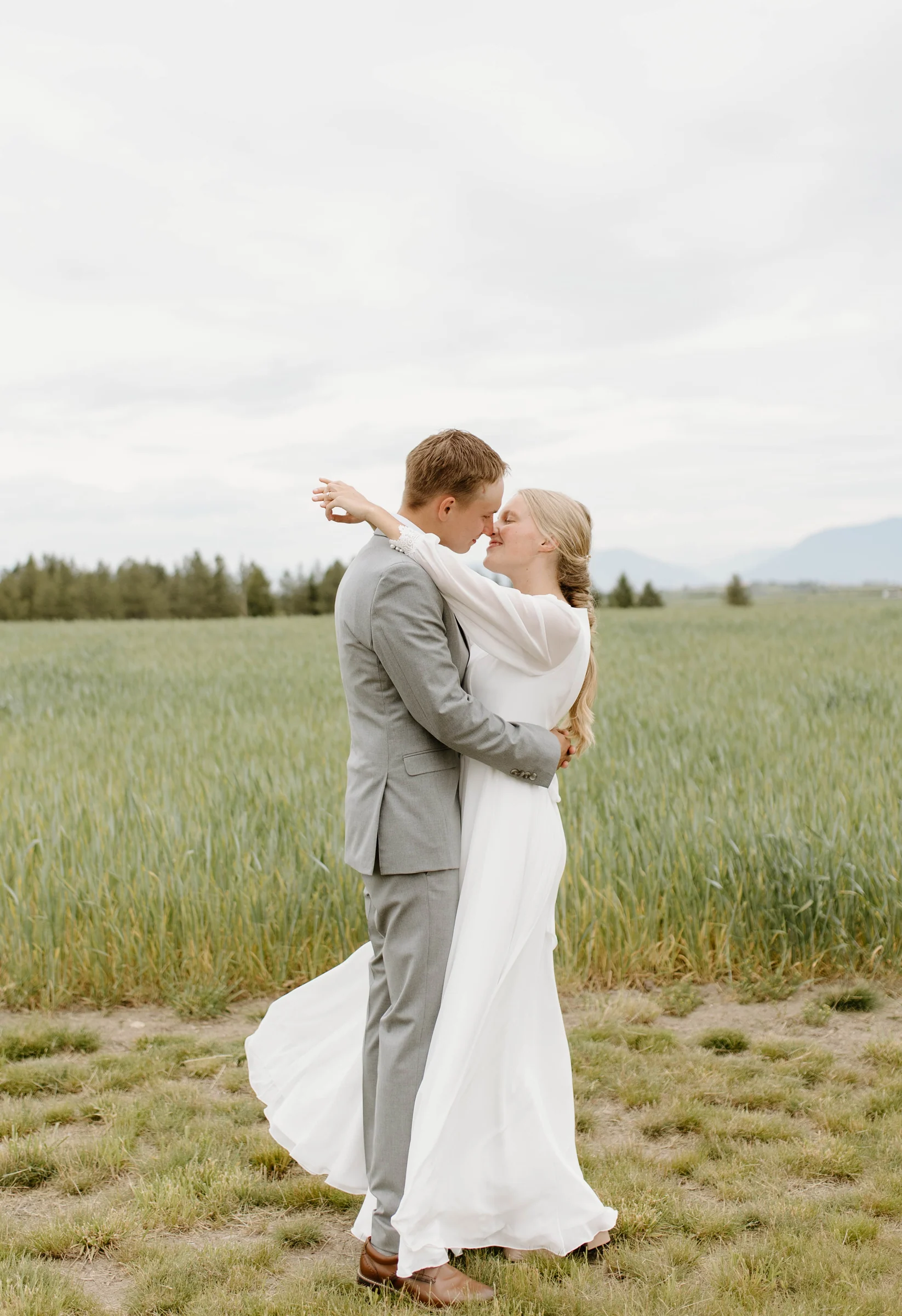 A bride and groom embracing on a grassy hillside
