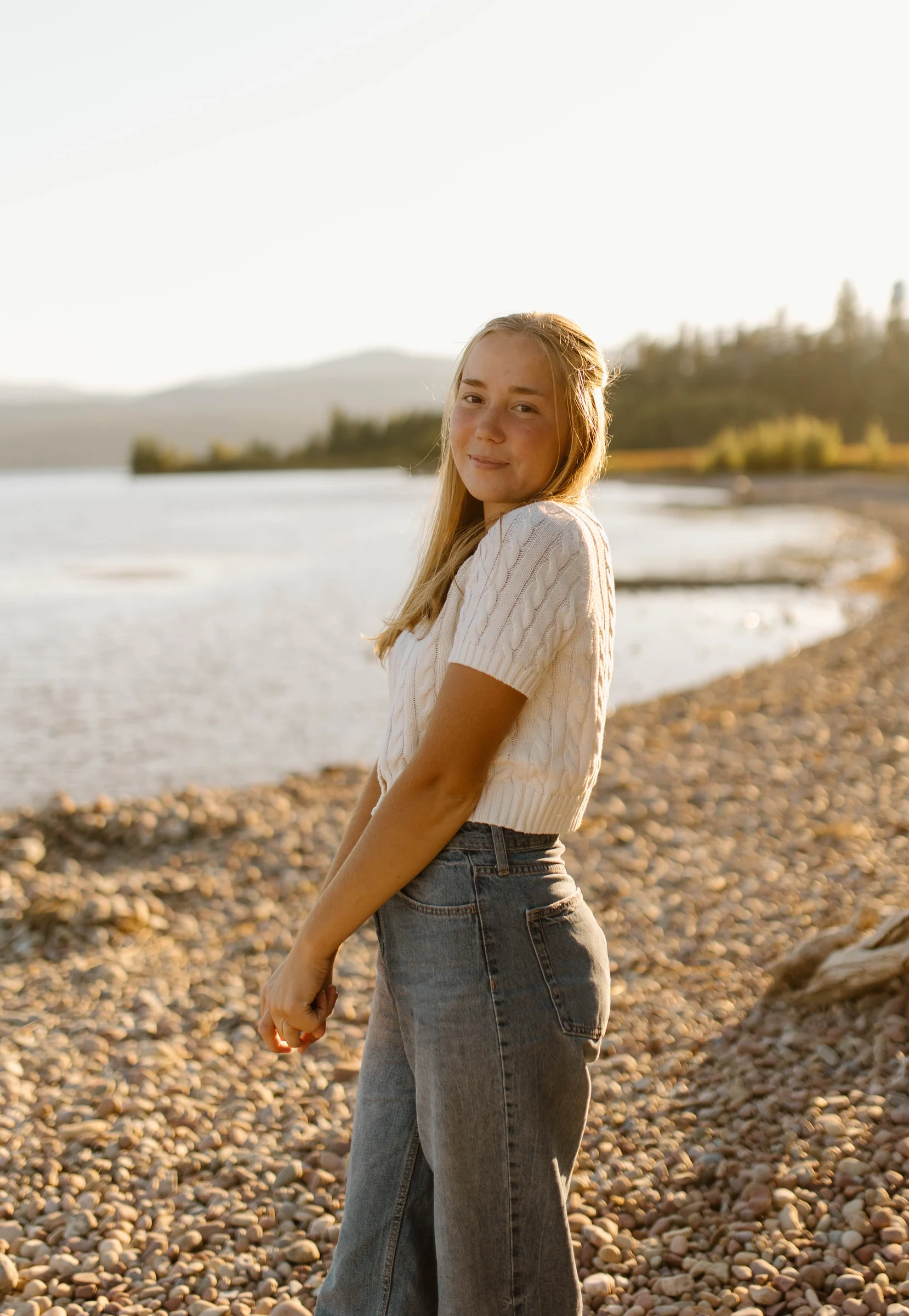 A senior portrait beside the lake in golden light