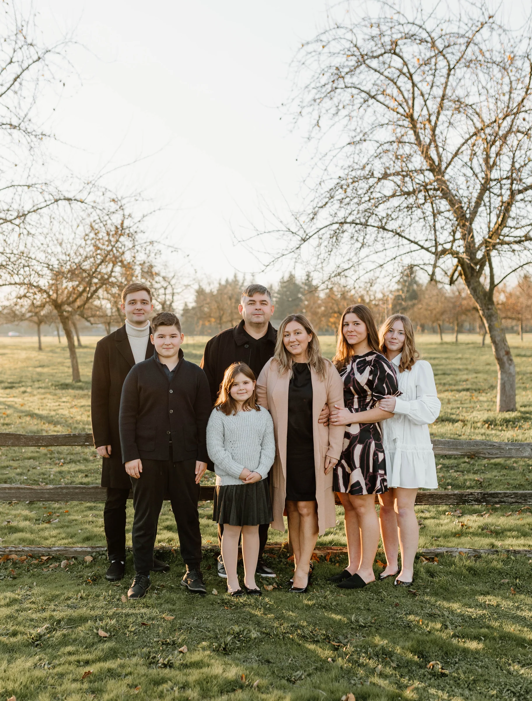 An extended family gathered beneath autumn trees