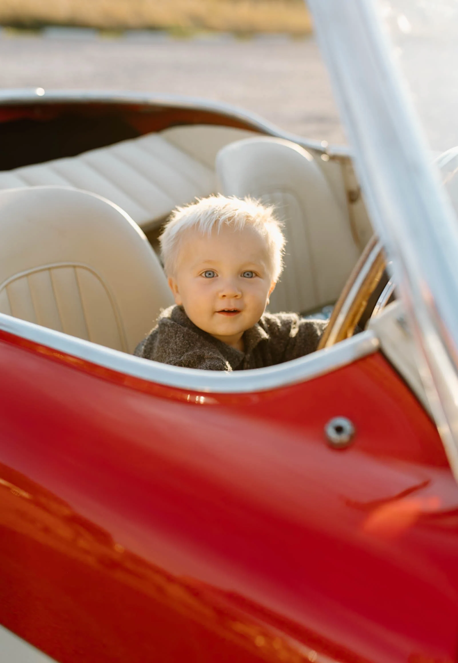 A baby sitting inside a red toy car