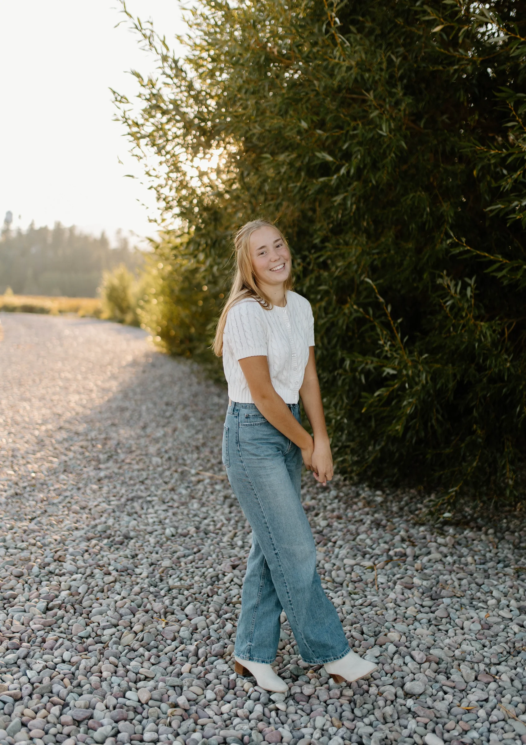 A senior portrait standing among shoreline stones